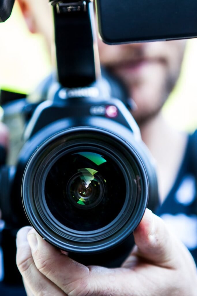 A close-up shot of a cameraman filming, focusing on the camera lens and equipment.
